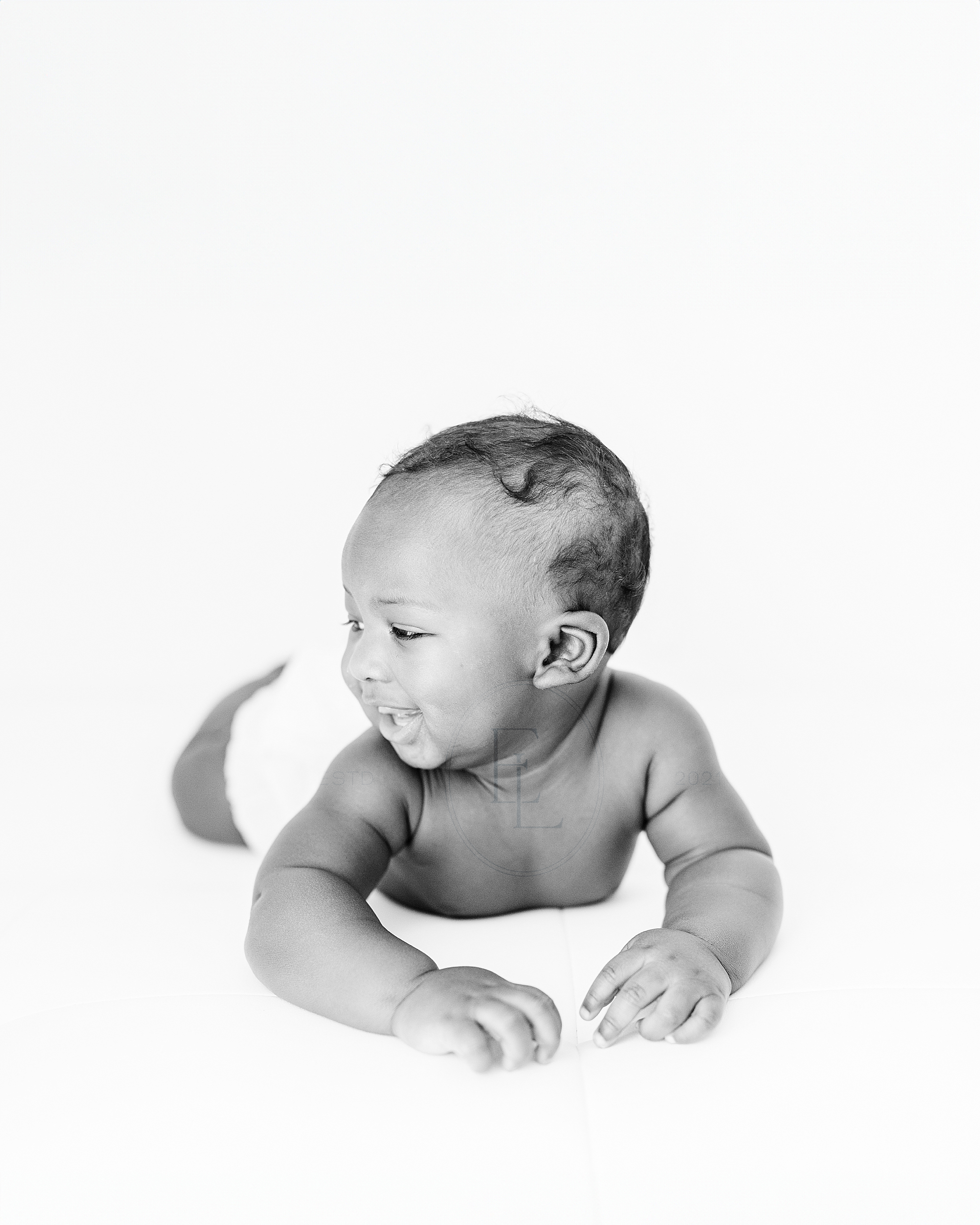 A 6 month old baby boy grins off to the side during his milestone session with Hattiesburg baby photographer Emily Lofton.