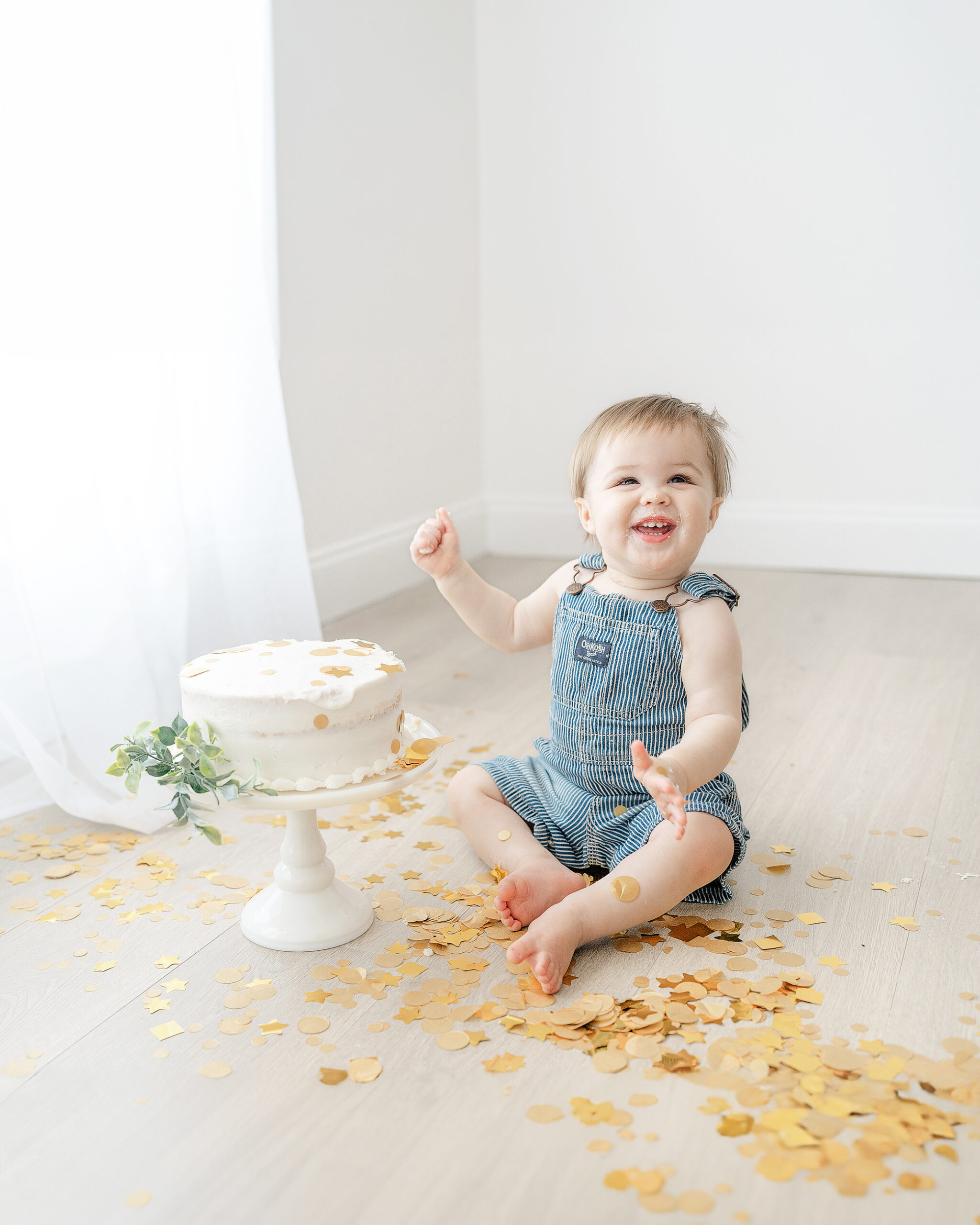 A baby boy smiles during his cake smash session with Emily Lofton Photography in Sumrall, MS.